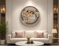 A framed circular wall art piece featuring a classical Indian painting of Radha Krishna, displayed in a modern living room setting above a light beige sofa. The image includes branding for  at the top and contact details at the bottom.